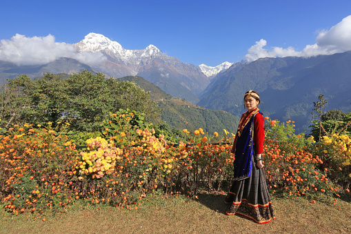 a girl with Gurung traditional dressing  in Ghandruk village, Gandaki Province of Nepal, annapurna south background . it is a point of Annapurna circuit trek and Poonhill trekking in Nepal