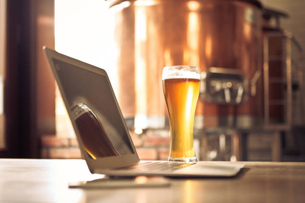 istock Laptop and beer pint glass in table at micro brewery 1977654390