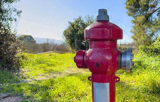 Fire fighting public system. Fire hydrant hose connection red color painted outdoors at a lawn, sunny day in Greece. Safety in extinguish.
