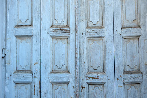 Wooden closed door background, texture. Light blue empty peeled worn board plank. Traditional Greek rural construction. Copy space