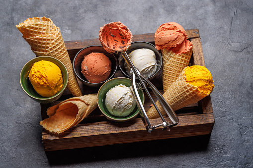 Assorted ice cream flavours in delightful waffle cones, a treat for every taste bud. Over stone background