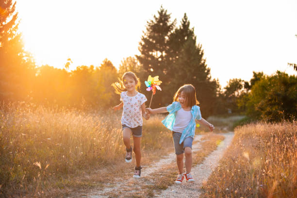Two happy little friends with rainbow pinwheel toy.