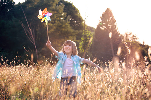 Cute happy little boy with rainbow pinwheel toy.