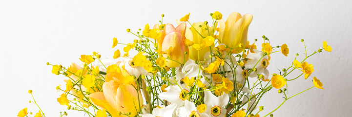 Spring bouquet of yellow buttercups, white daffodils and tulips, bouquet of flowers close up, home decoration with flowers