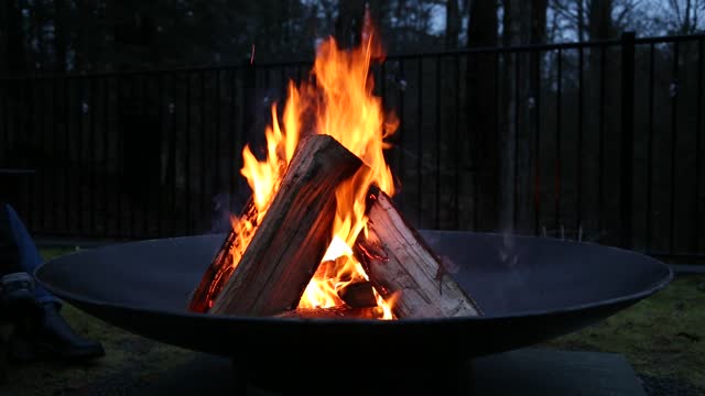 fire burning in fire pit (wood logs ablaze with orange flames) outdoor camping, relaxing scene