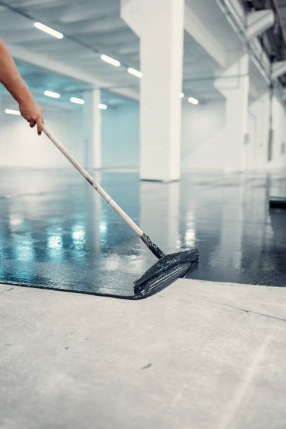 istock Worker applies gray epoxy reisin to a new floor. Modern Surface 1977712563