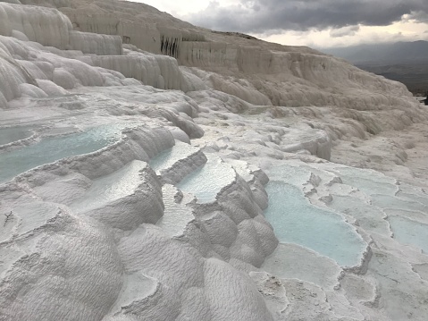 Embark on a journey to Pamukkale's enchanting travertine terraces, where inviting thermal pools await beneath the ever-changing cloudy skies. Experience the serene beauty of this natural wonder as you soak in the soothing waters and marvel at the breathtaking landscape.