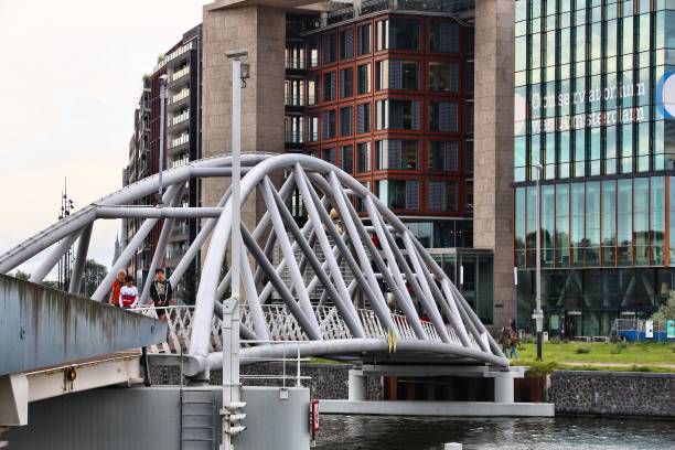People walk the modern Oosterdok footbridge in Amsterdam, Netherlands.