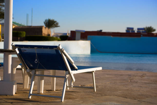 Sun lounger under a sun umbrella near the pool in a hotel, a place to relax outdoors on vacation