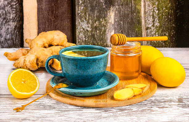 istock Healing tea with ginger root in a blue cup, honey, pieces of ginger and lemons. 1977763785