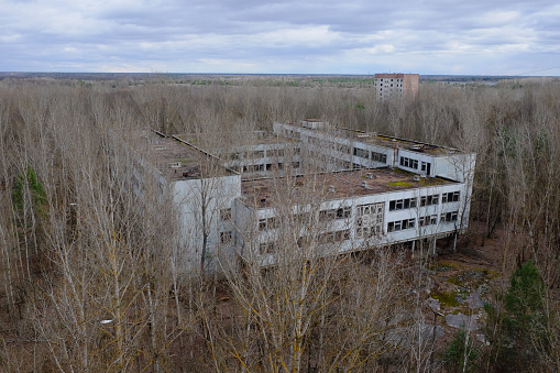 An abandoned concrete building among the trees in Pripyat. Aerial view. Cloudy weather, landscape.