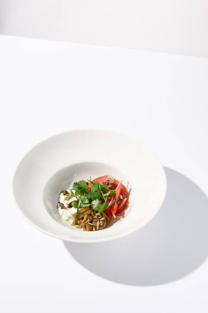 istock Artful salad with tomatoes, stracciatella cheese, and eggplants garnished with cilantro on a modern white bowl 1977794181
