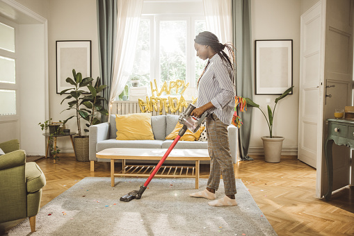 Mother vacuuming living room after birthday party.