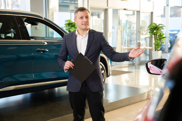 istock Salesman points his hand at a new car 1977809101