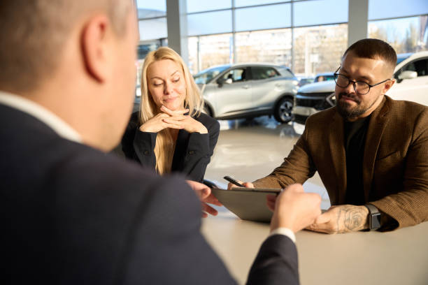 istock Two buyers looking at a car purchase agreement 1977812297