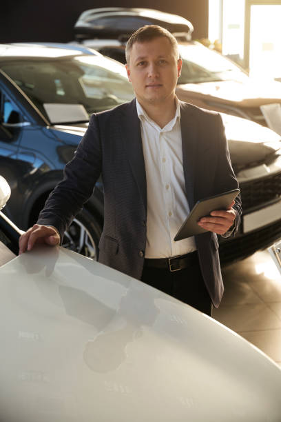 istock Dealer watching with camera next to car 1977813384