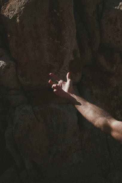 istock human arm in sunlight surrounded by a shadow in a bay surrounded by a hill of stone and granite, Crete, Greece 1977828021