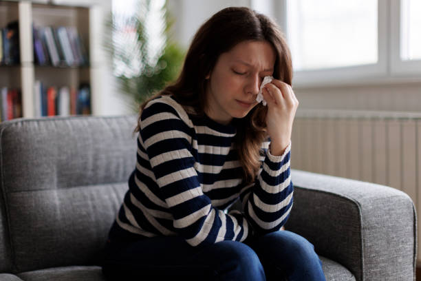 istock Young woman sitting on sofa and crying 1977837375
