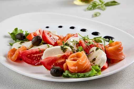 Salmon and mozzarella Caprese salad with fresh tomatoes, top view. Ideal for culinary magazines and healthy eating blogs.