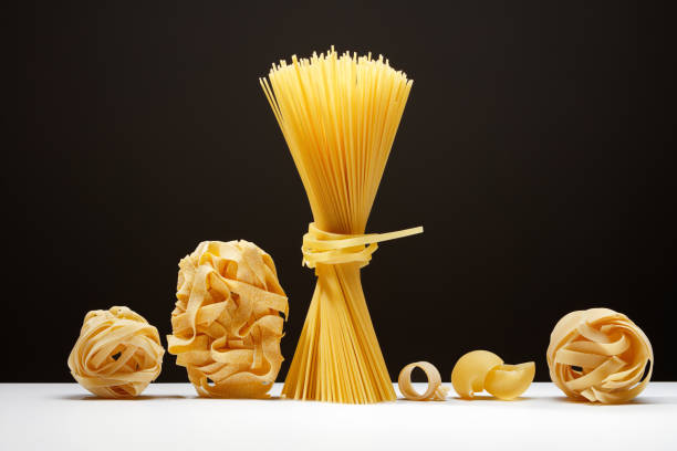 istock Various types of dry pasta on a black background and white table. 1977855057