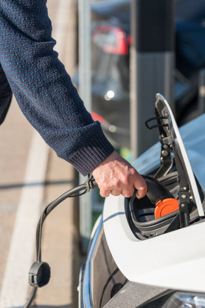 istock Hand plugging charger into electric car 1977874421