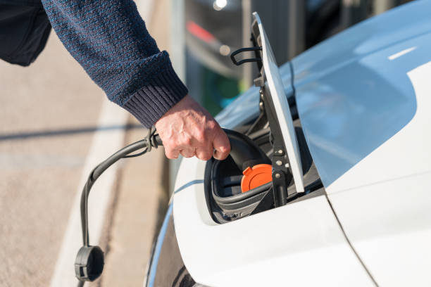 istock Man inserts a power cord into an electric car 1977874434