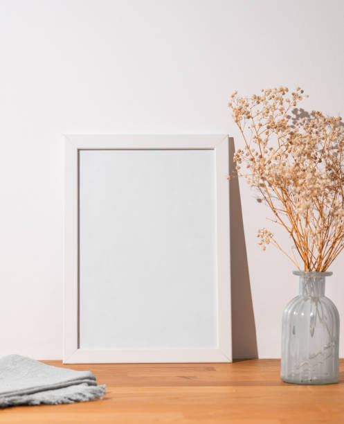 istock A  white frame with a blank canvas against a light wall and on a wooden tabletop with vase 1977903706