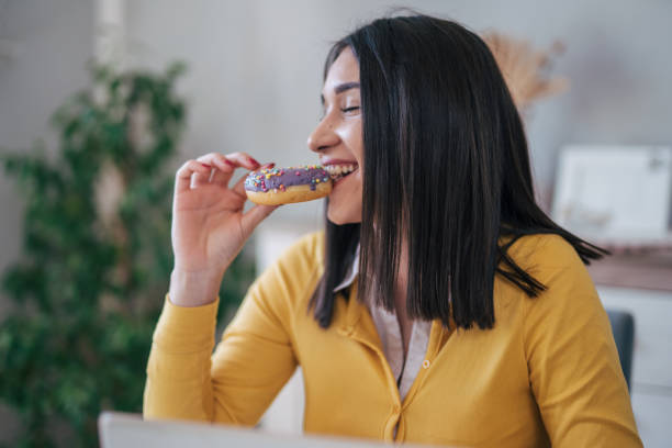 istock Profile view of young woman eating doughnut 1977905281