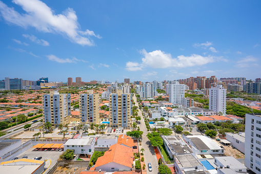 This captivating photograph presents a stunning midday view of the Barranquilla skyline, a prominent city located in Colombia. Captured under the brilliance of a clear blue sky, the image showcases the vibrant and dynamic urban landscape of this coastal metropolis. The city's architecture, a blend of modern structures and cultural landmarks, is highlighted against the backdrop of the Caribbean Sea and the Magdalena River, creating a picturesque urban tapestry.

Barranquilla's skyline is defined by a variety of high-rise buildings that speak to its status as a significant commercial hub and a center of urban development in South America. These skyscrapers, each with their unique architectural style, punctuate the horizon, creating a striking contrast against the tropical blue skies. The photograph, taken from an aerial perspective, offers a panoramic view that encapsulates the city's urban sprawl and its architectural diversity.

The bright sunlight of noon enhances the vibrancy of the cityscape, illuminating the facades of the buildings and casting gentle shadows that add depth and dimension to the scene. This image not only captures the physical beauty of Barranquilla's urban landscape but also conveys the bustling energy and the spirit of a city that is continuously growing and evolving.

Overall, this photograph of Barranquilla's skyline is not just a visual representation of the city's physical attributes; it is a testament to its cultural richness, economic vitality, and the urban beauty that characterizes this prominent Colombian city.
