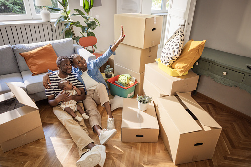 Young family with baby in their new home. They are surrounded by cardboard boxes