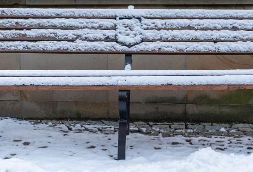 White snow on a bench close-up on blurred pavement background