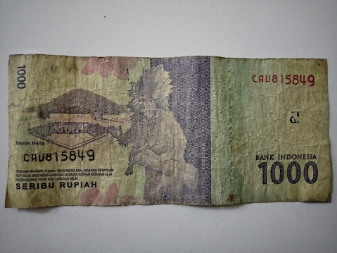 One thousand Indonesian rupiah banknotes that are crumpled and dull in color