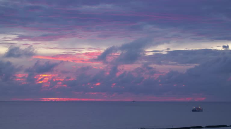 Ship silhouette against a vibrant sunset sky at sea in 4k