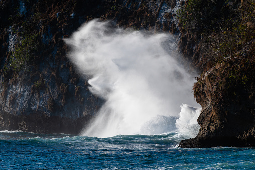 A Wave Is Crashing Spraying White Sea Water On A Rugged Coastline Beach Rock