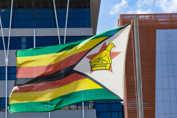 istock zimbabwe flag on the pole, blue sky with clouds 1978087226