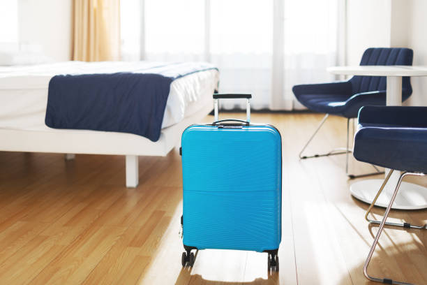 Blue plastic cabin case suitcase at hotel room ready for trip - foto de stock