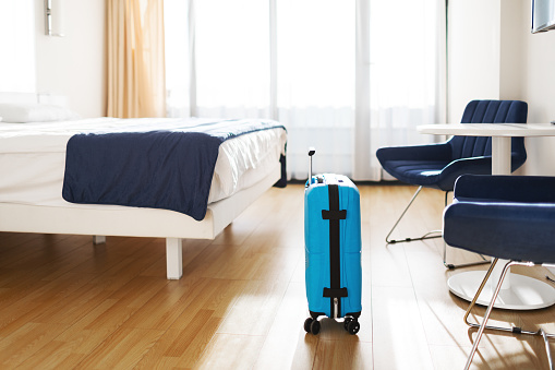 Blue plastic cabin case suitcase at hotel room ready for trip
