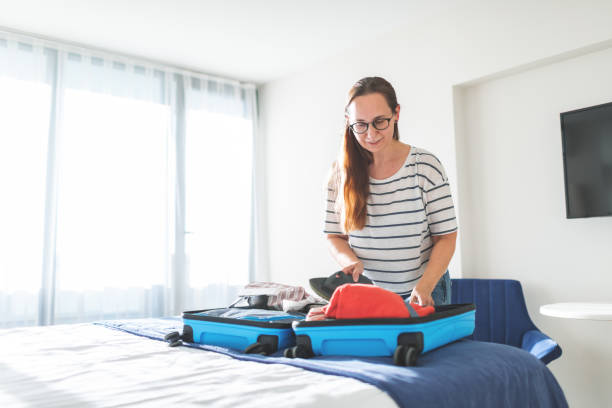 istock Mid adult woman packing clothes suitcase 1978120546