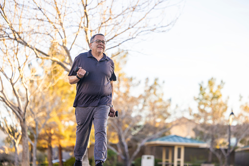A Hispanic Senior working out outdoors at a park.