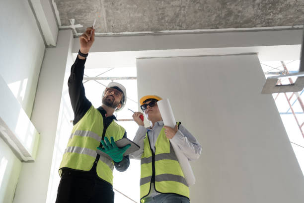 istock Caucasian engineer man and woman working with tablet computer and paper work at construction site 1978130572