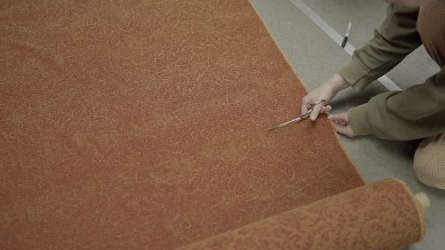 tailor seamstress cuts upholstery fabric.