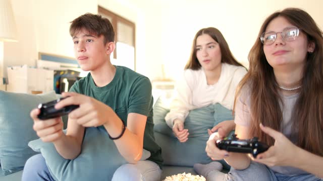 Two teenagers are playing console games in a living room