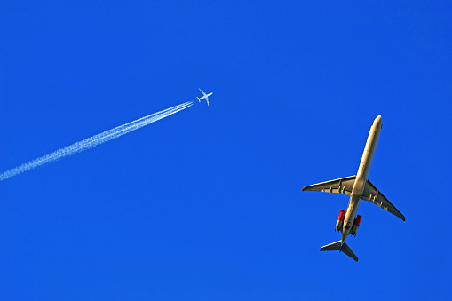 a low-flying and a high-flying passenger plane in the blue sky