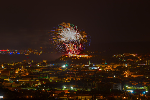 Fireworks over the night city of Brno in the Czech Republic in Europe. Above the city are different colored shapes of flares.