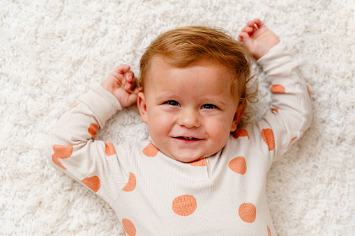 Above shot of baby boy’s portrait lying on a carpet and smiling