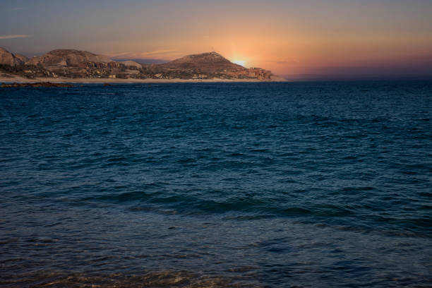 Sun setting over the sea and desert in Cabo San Lucas, Mexico