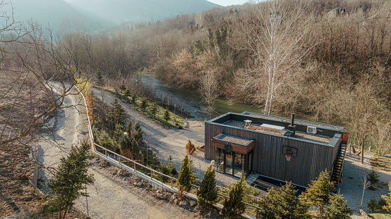 Photo of a wooden cabin house on a riverbank // aerial view