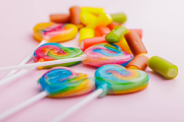 Heart shaped lollipop. Sweet candy on the pink background.