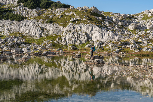 Women standing on the rock in the middle of one of Seven Triglav's lakes on sunny day. Julian Alps, Slovenia
