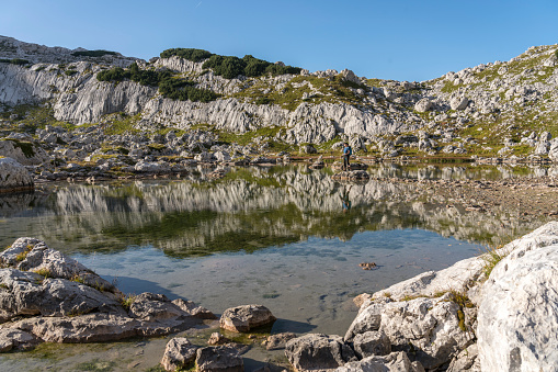 Women standing on the rock in the middle of one of Seven Triglav's lakes on sunny day. Julian Alps, Slovenia